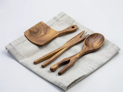 A set of wooden cooking utensils: spatula, spoon, tongs, arranged on a linen clo