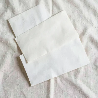 Top-down arrangement of three folded letters stacked unevenly on cream linen