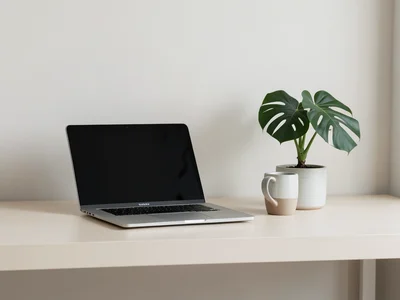 Clean minimal home office desk with laptop, ceramic mug, and a single monstera p