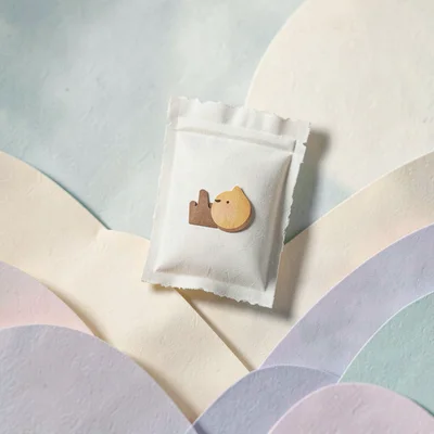 Papercraft scene of a tiny cut-paper snack pouch in a paper landscape, soft past