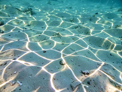 Caustic light pattern dancing on sandy bottom at one meter depth