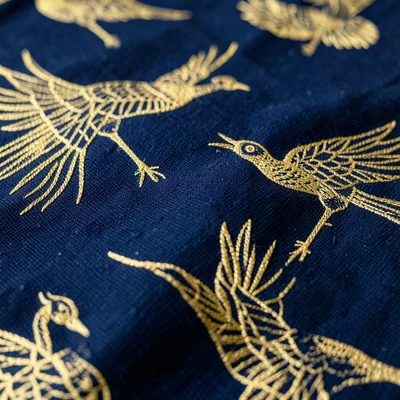 Vintage kimono fabric pattern, gold thread cranes on deep indigo, macro detail