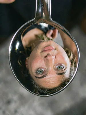 A face reflected in a spoon, features stretched and inverted