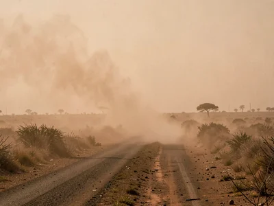 Road disappearing into dust haze thirty meters ahead