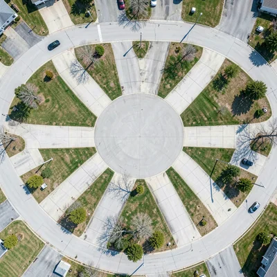 Suburban cul-de-sac from directly above, identical driveways radiating like flow