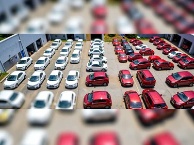 Garage-roof tilt-shift photograph of a car-rental yard, saturated white hatchbac