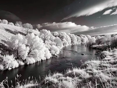 A winding river seen from a low hill — white-lit banks, dark water, dramatic sky