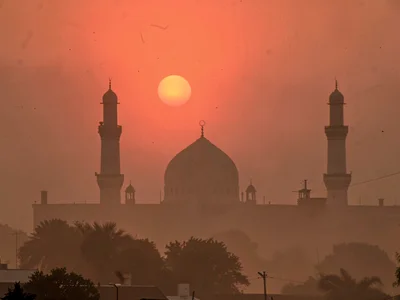 Mosque silhouette against dust-red setting sun