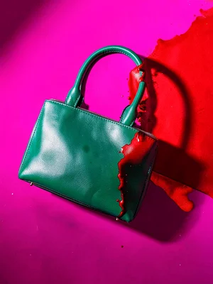 Emerald leather handbag on a magenta surface — the two rich tones fighting at th