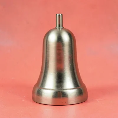 desktop bell-shaped paperweight in brushed brass straight-on against a saturated
