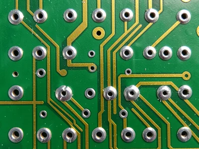 A macro of solder joints on a wave-soldered through-hole PCB — shiny silver fill