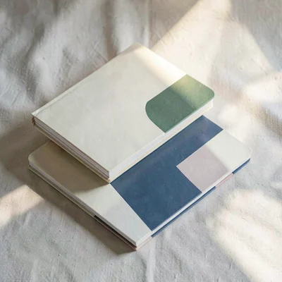 A trio of abstract notebook-cover mockups stacked diagonally on a soft canvas ba