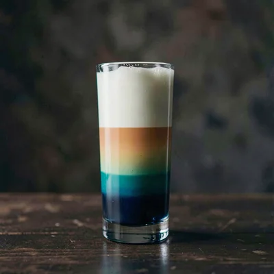 Vertical moody scene of a tall highball with stratified color layers