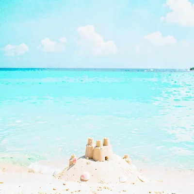 Expansive turquoise negative space, bleached whites, A childs sandcastle, simple