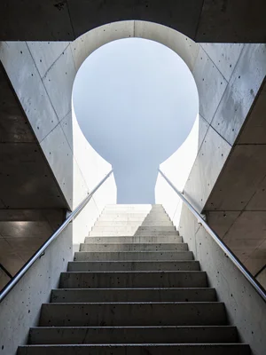 Concrete staircase viewed straight up, steps receding into circle of sky