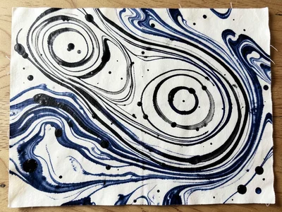 Suminagashi floating ink rings, concentric circles in black and indigo drifting 