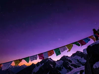 Prayer flags catching alpine wind against deepening violet sky