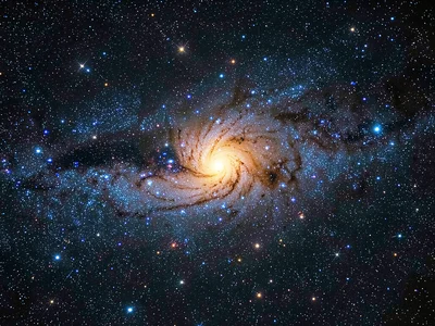 A face-on spiral galaxy with blue-white young star clusters in the arms and a wa