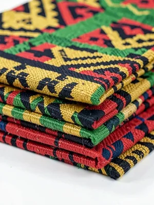 Stack of folded kente cloth strips — layers of color bands, side view