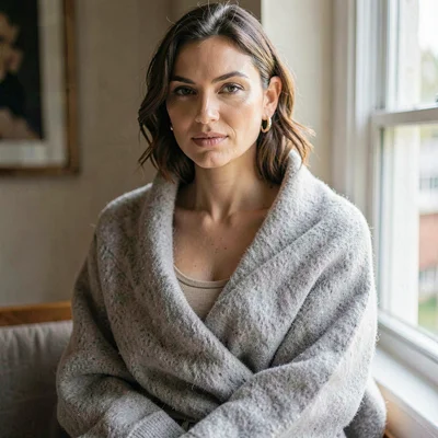 Editorial portrait of a model wrapped in a soft wool throw, oat tank visible und