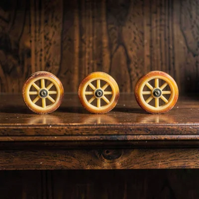 A row of three small wheels on a deep walnut shelf, graduated by rind colour, wa
