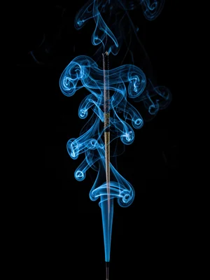 A single column of incense smoke rising straight then exploding into turbulent s