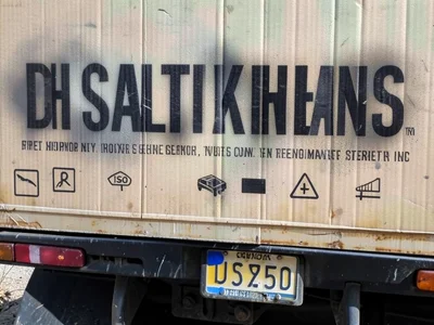 The side of a delivery van with a company name in vinyl applied over older faded