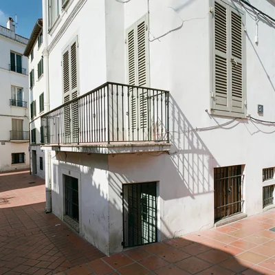 Siesta stillness, afternoon heat weight, An iron balcony casting grid shadows on
