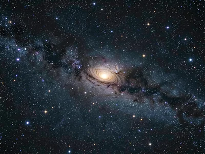 An edge-on spiral galaxy seen in profile against a dense star field, its dust la