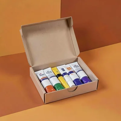 Catalog hero of an open oil paint box with tubes inside on terracotta backdrop