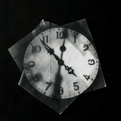 A photogram of a clock face — hands and numerals as shadow silhouette, no visibl