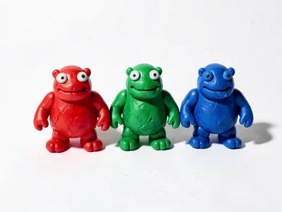 Family of three chunky clay slime monsters in red green and blue, arranged in a