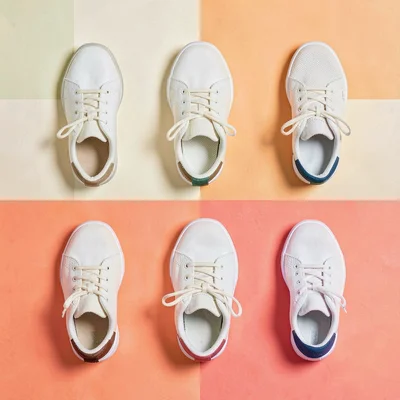 Color-block grid flatlay of six pairs of socks tucked into sneakers on coral pap