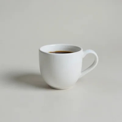 Minimalist photography of a single white coffee cup on a plain matte surface, clean studio lighting, soft natural shadow