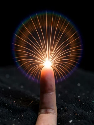 A human fingertip centered on dark ground, orange-white plasma discharge fan fro