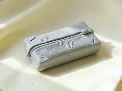 Calm putty-grey pencil case with thumb dents along the zipper and fingernail den