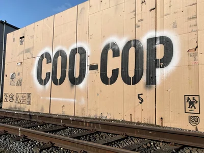 A grain elevator wall with the co-op name in ten-foot-tall stenciled letters, fa
