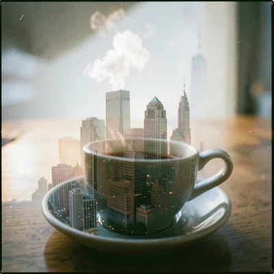 A coffee cup double-exposed with a morning cityscape, steam and skyscrapers risi