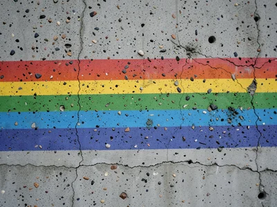 Brutalist concrete wall with rainbow mural painted boldly across surface