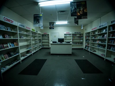 The interior of a recently closed video rental store, empty shelving units linin