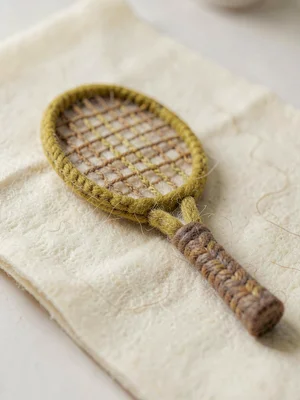 Curve-handled mustard knit tennis-racket with cable-knit strings and a felted gr