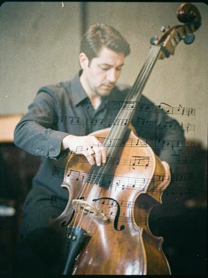 A musician playing cello, double-exposed with sheet music, the notes appearing t
