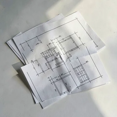 Top-down arrangement of three folded blueprint sheets stacked unevenly, soft aft