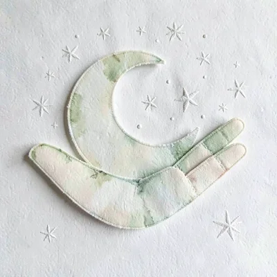 Layered papercraft of a crescent moon nestled inside an open palm, ivory and sag