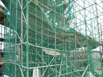 Scaffolding wrapped in green mesh, the chaos of construction contained in grid
