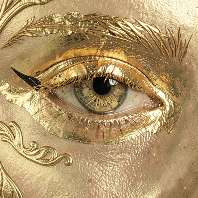 A close-up of an eye with gold leaf gilded over the iris and lash line