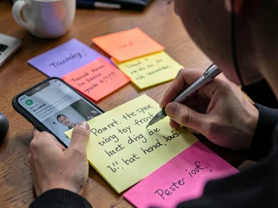Person writing sticky note while on phone, the capture of fleeting information, 