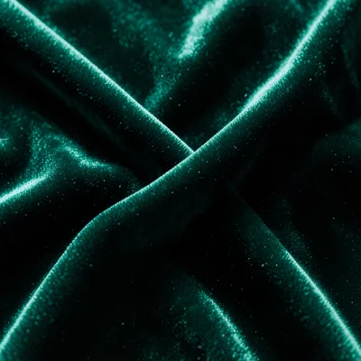 Velvet fabric in deep emerald, light catching the nap, luxurious folds