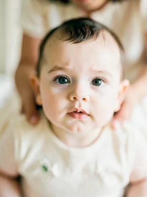 Baby's face in focus, parent's arms blurred