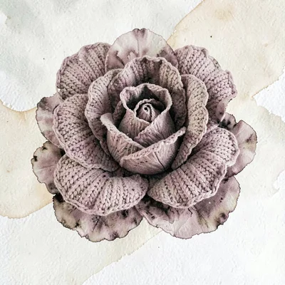 Layered dusty-rose knit cabbage rose with chunky overlapping petals, on warm cre